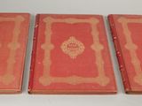 three red books sitting on top of a table next to each other
