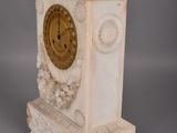 a white clock with a gold face on a pedestal