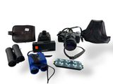 un appareil photo, un étui pour appareil photo, un appareil photo et d'autres objets disposés sur une surface blanche