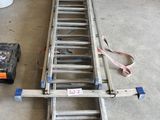 une échelle posée par terre à côté d'une boîte à outils