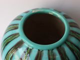 a blue vase with a green handle on a white table