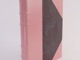 a pink book with a black cover on a white surface