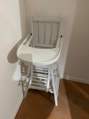 une chaise haute blanche pour bébé, dans un coin de la pièce