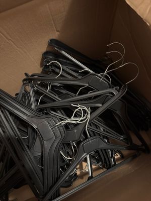 une boîte en carton remplie d'un grand nombre de cintres noirs