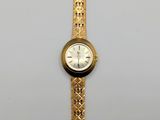 a gold wrist watch with a white face on a white surface