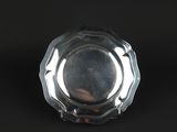 an antique silver plate on a black background with a reflection