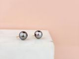 une paire de boucles d'oreilles en perles noires posée sur un bloc de marbre