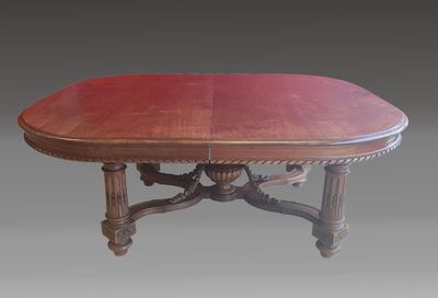 une table à manger ovale avec un plateau rouge et des pieds sculptés