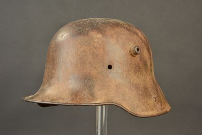 an old helmet on a metal stand against a gray background