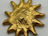 a gold sunflower brooch on a white surface