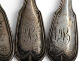 three silver spoons with monograms on them sitting on a white surface