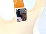 a close up of a white electric guitar on a stand