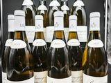 Des bouteilles de vin blanc sont alignées sur une table noire