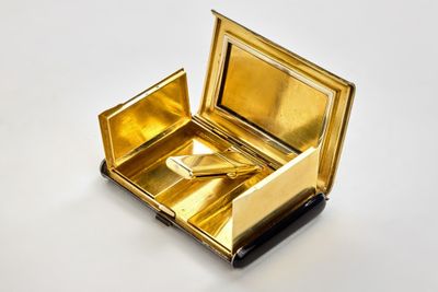 a small gold box with a pair of scissors in it
