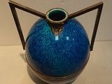 a blue vase with a gold handle sitting on a table
