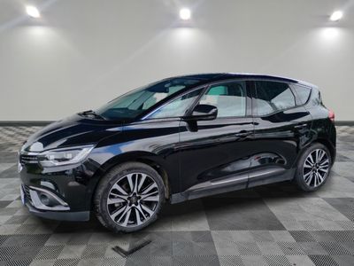 Une voiture noire est garée dans une grande pièce au sol à carreaux.