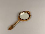 an antique mirror with a gold frame and a wooden handle