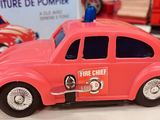 a pink toy car with a fire truck in the background