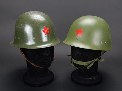 deux casques verts ornés d'étoiles rouges, posés l'un à côté de l'autre
