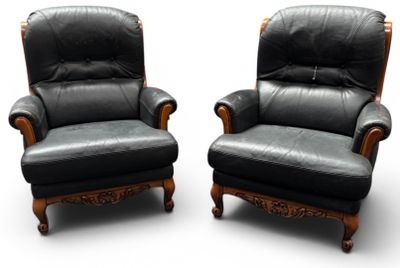 une paire de fauteuils inclinables en cuir noir, avec des accoudoirs et des pieds en bois sculpté
