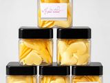 four jars filled with yellow heart shaped buttons on top of each other