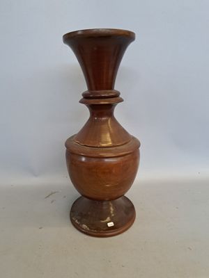 a brown vase sitting on a table with a white wall in the background