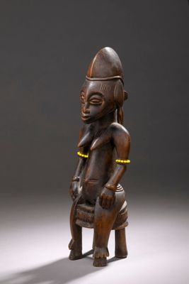 une photo représentant la statue d'un homme assis sur un tabouret