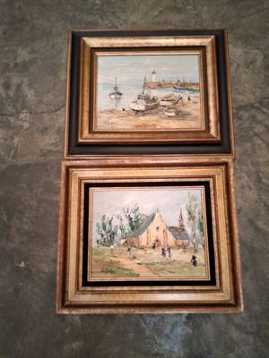 deux tableaux encadrés accrochés au mur d'une salle de bains équipée de toilettes et d'un lavabo