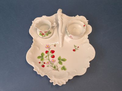 une assiette blanche sur laquelle sont posées deux tasses et une soucoupe