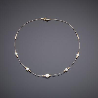 a gold and pearl necklace on a gray background