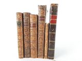 several old books are stacked on top of each other on a white surface