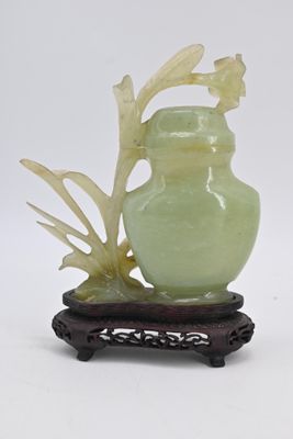 un vase vert orné d'une feuille, posé sur un socle