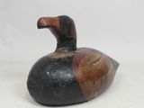 an image of a black and brown duck sitting on top of a white surface