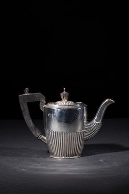 a silver teapot on a black surface with a black background