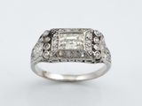 une bague en or blanc sertie d'un diamant taille princesse entouré de petits diamants