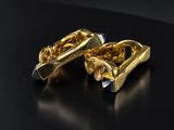 a pair of gold cufflinks on a black surface