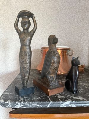 une statue représentant une femme et un chat assis sur une table