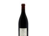 the bottle of red wine is sitting on a white surface