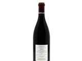 the bottle of red wine is sitting on a white surface