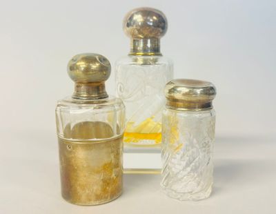 trois flacons de parfum posés l'un à côté de l'autre sur une table