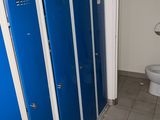 trois casiers bleus dans une salle de bains avec des toilettes dans un coin