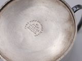 an image of a silver cup with a handle on a white surface