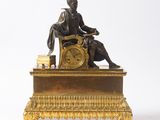 une statue d'un homme assis au sommet d'une horloge