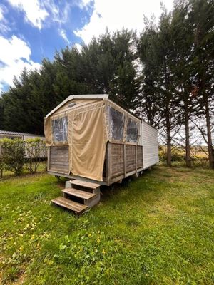 une photo d'un mobil-home au milieu d'un champ