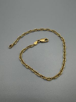 un bracelet en chaîne d'or muni d'un fermoir, posé sur une surface grise