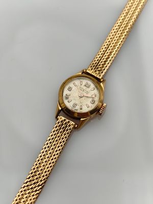 a close up of a gold watch on a white surface