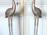 deux flamants roses en métal placés l'un à côté de l'autre sur un plancher en bois