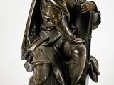 statue en bronze représentant un homme assis sur une chaise avec un chien