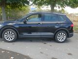 the black volkswagen suv is parked on the side of the road