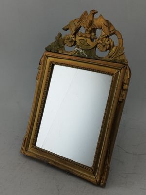 un miroir avec un cadre doré sur lequel est représenté un oiseau